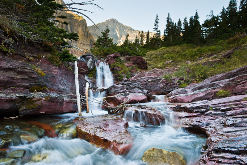 Baring Creek tumbles and falls over red sedimentary rocks in Glacier National Park, Montana, USA.